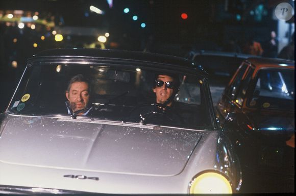 Archives - Serge Gainsbourg et Thierry Ardisson en "peugeot 404 lors de l'émission "Lunettes noires pour nuits blanches" à Paris en 1989. (AGENCE / BESTIMAGE).