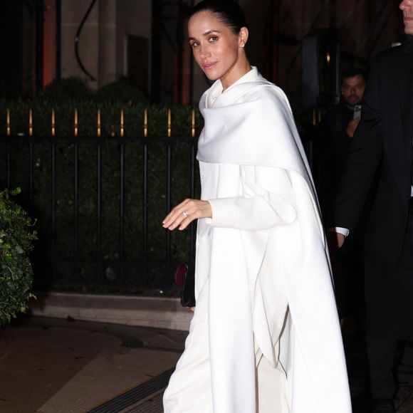 Paris, FRANCE  Meghan Markle, la duchesse de Sussex, a été aperçue à son arrivée à l'Hôtel Plaza Athénée à Paris, resplendissante dans une élégante cape blanche oversize assortie à des escarpins noirs à bout pointu. Backgrid USA / Bestimage