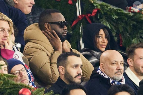 Gims et sa femme DemDem dans les tribunes du match de Ligue 1 McDonald's opposant le Paris Saint-Germain (PSG) à Lyon (3-1) au Parc des Princes à Paris le 15 décembre 2024. © Cyril Moreau/Bestimage