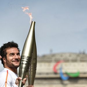 Le chanteur franco-israélien Amir Haddad transmet la flamme olympique à la pâtissière française Nina Metayer sur les Champs-Elysées devant l'Arc de Triomphe lors du relais de la flamme olympique à Paris le 15 juillet 2024. Photo by Firas Abdullah/ABACAPRESS.COM