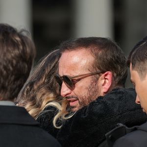 Michel Ferracci serre dans ses bras sa belle-fille, Milla Savarese, la fille de la défunte, sous le regard de ses fils Maël et Enzo Ferracci à la sortie des obsèques d'Emilie Dequenne au cimetière Père Lachaise à Paris, France, le 26 mars 2025. © Cyril Moreau/Bestimage