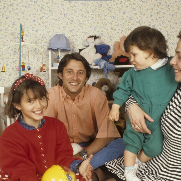 Archives - En France, à Neuilly-Sur-Seine, dans une chambre d'enfant, portrait de Antoine de Caunes assis par terre, avec sa compagne Agnès Leglise tenant leur fils Louis de Caunes, et sa fille Emma de Caunes coiffée d'un serre-tête et tenant un jouet. Date inconnue
© Michel Ristroph via Bestimage