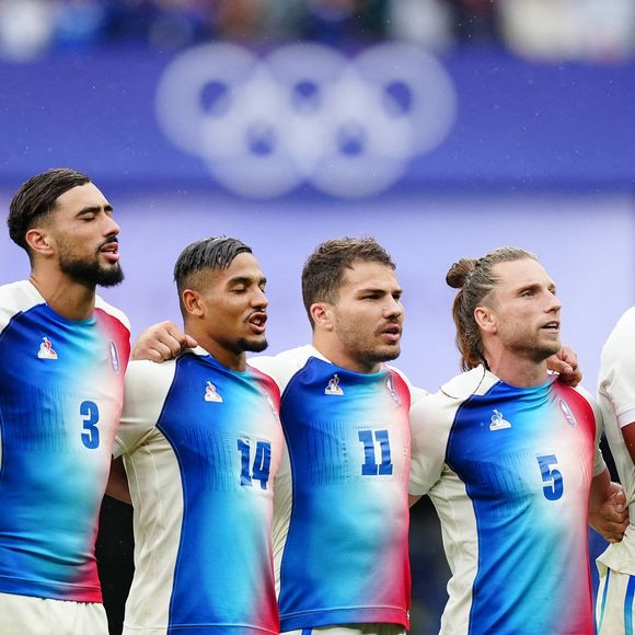 Le 27 juillet 2024, lors des Jeux Olympiques sur le sol parisien, Antoine Dupont et ses coéquipiers sont parvenus à faire la différence et à devenir champions olympiques grâce à leur incroyable performance sur le terrain face à l’équipe des Fidji.

Le Français Antoine Dupont et ses coéquipiers se lèvent pour les hymnes nationaux lors du match pour la médaille d'or de rugby à sept au Stade de France, le premier jour des Jeux Olympiques de Paris 2024 en France. Date de la photo : samedi 27 juillet 2024. © PA Photos