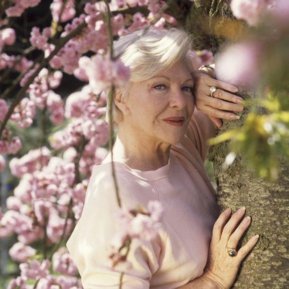 En France, à Rueil-Malmaison, rendez-vous avec Line RENAUD dans le jardin de son domicile "LA JONCHERE", s'appuyant contre le tronc d'un cerisier en fleurs, offert par MICHEL AUDIARD. Avril 1989 © Alain Canu via Bestimage