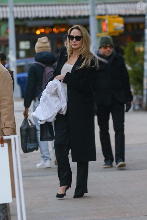 New York, NY - EXCLUSIF - Angelina Jolie respire l'élégance dans un costume noir et une chemise blanche, affichant un sourire radieux alors qu'elle sort les mains pleines du studio Atelier Jolie à New York. (Backgrid USA / Bestimage).