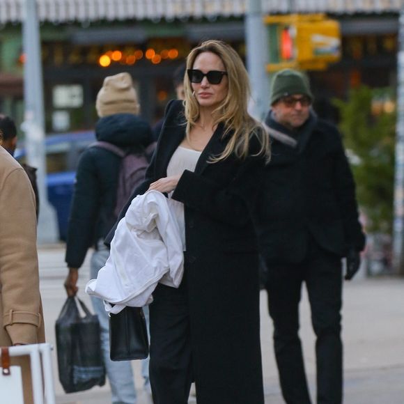 New York, NY - EXCLUSIF - Angelina Jolie respire l'élégance dans un costume noir et une chemise blanche, affichant un sourire radieux alors qu'elle sort les mains pleines du studio Atelier Jolie à New York. (Backgrid USA / Bestimage).