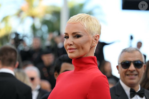 Détendue, elle revient avec humour sur son nouveau look et raconte la petite phrase du chanteur qui a tout déclenché : “Mon mec m’a dit : tu ressembles à David Bowie. Je dis, pardon, à qui ? Mais c’est un mec”. 

Adriana Karembeu - Montée des marches du film "La Bataille de Gaulle : L'âge de fer" lors du 79ème Festival International du Film de Cannes, le 20 mai 2026.
© Rachid Bellak/Bestimage