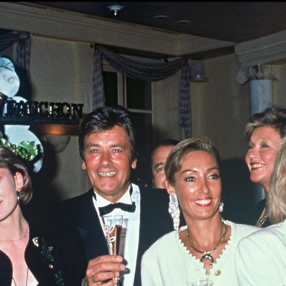 Archives - Patricia Kaas, Alain Delon et Marie Fugain lors de la soirée pour le lancement du champagne "Alain Delon" en 1990 à Paris.@ANGELI-RINDOFF / BESTIMAGE