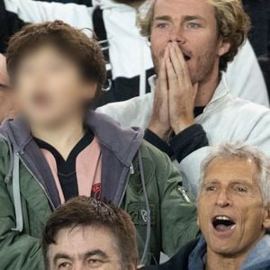 Nagui et son fils Adrien Fam - Célébrités dans les tribunes du match de Ligue des Champions entre le PSG contre le Bayern de Munich (1-2) au Parc des Princes à Paris le 4 novembre 2025. © Cyril Moreau/Bestimage