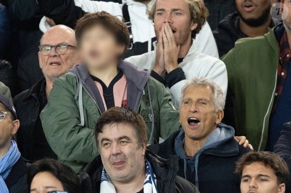 Nagui et son fils Adrien Fam - Célébrités dans les tribunes du match de Ligue des Champions entre le PSG contre le Bayern de Munich (1-2) au Parc des Princes à Paris le 4 novembre 2025. © Cyril Moreau/Bestimage
