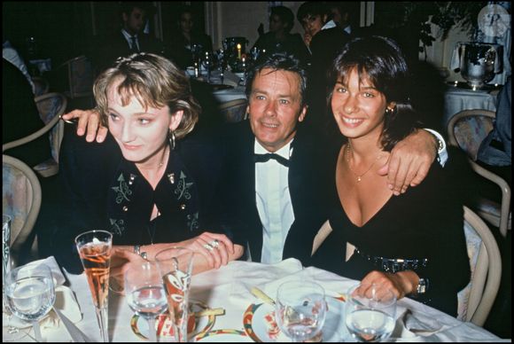 Archives - Patricia Kaas, Alain Delon et Marie Fugain lors de la soirée pour le lancement du champagne "Alain Delon" en 1990 à Paris.@ANGELI-RINDOFF / BESTIMAGE