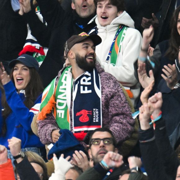 Iris Mittenaere, Jean Dujardin, Oli - Célébrités dans les tribunes du match d'ouverture du Tournoi des six nations : France-Irlande (36-14) au Stade de France à Saint-Denis le 5 février 2026. © Lionel Urman/Bestimage