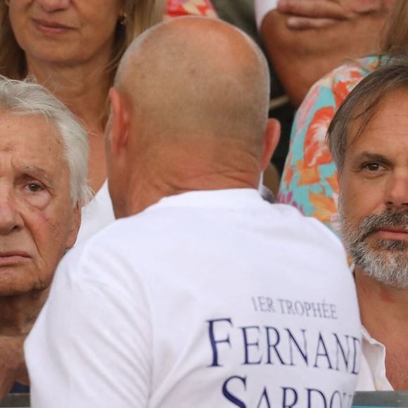 Semi-exclusif - Michel Sardou, Romain Sardou - Michel Sardou rend hommage à son père en famille lors du premier trophée de pétanque "Fernand Sardou" à Bormes-les-Mimosas le 29 mai 2026. Le célèbre chanteur est venu en famille avec sa femme, son fils Romain avec son fils de deux ans et demi et de sa compagne enceinte de son deuxième enfant.
La première édition du Trophée Fernand Sardou est organisée du 29 au 31 mai au coeur du village de Bormes les Mimosas. Une initiative portée par Michel et son fils Romain, pour rendre hommage à leur illustre parent Fernand Sardou au travers d'un tournoi de pétanque.
En lien avec la municipalité et l'Amicale Bouliste Borméenne (ABB), un premier Trophée Fernand Sardou sera organisé avec deux grands temps forts : Le vendredi, dès 18h, un tournoi d'exhibition sera proposé et verra s'affronter 16 triplettes. Puis un concours fédéral à pétanque sera organisé le weekend et ouvert à tous les amateurs. 128 équipes seront réparties sur les sites les plus emblématiques du village, à savoir au boulodrome de la place Saint-François, mais aussi au parc Cigalou, sur le site du château et à l'ancien stade. © Franz Chavaroche/Bestimage