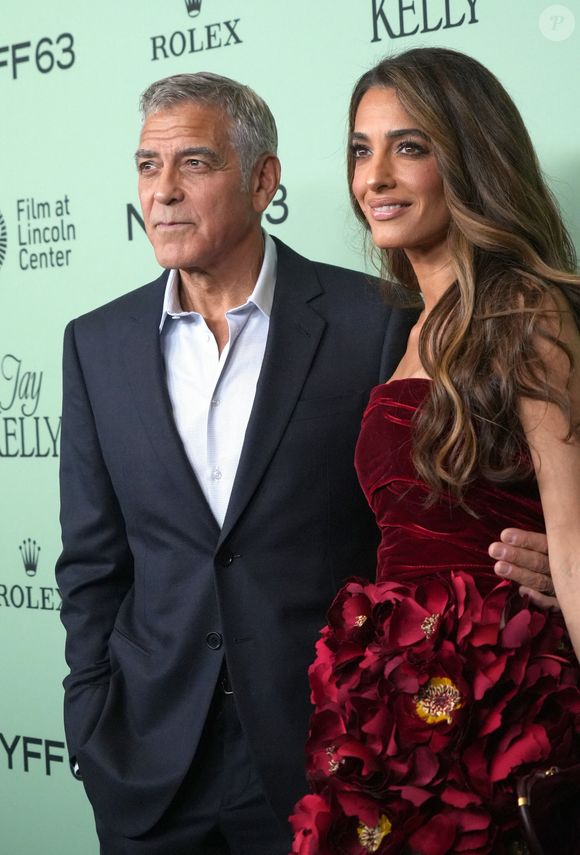 Escarpins dorés, pochette assortie et bijoux scintillants complétaient son look.
George Clonney et Amal Clooney assistent à la première sur le tapis rouge de « Jay Kelly » lors de la soirée d'ouverture du 63e Festival du film de New York. Alice Tully Hall, Lincoln Center, New York. 29 septembre 2025.  © Sonia Moskowitz Gordon/ZUMA Press Wire