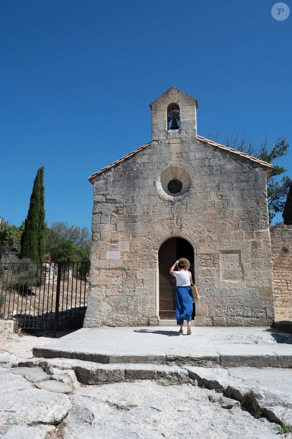 Les Baux de Provence (13) : la chapelle Sainte Blaise, femme de dos enlevant son chapeau sur le perron de la chapelle romane - Photo de Delmarty J/ANDBZ/ABACAPRESS.COM