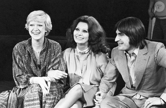 Archive - Serge Lama. En France, à Paris, sur le plateau, assis côte à côte de gauche à droite, se donnant le bras, Alice Dona, en robe, Sophia Loren, en robe et Serge Lama, en en costume cravate. © Michel Ristroph via Bestimage