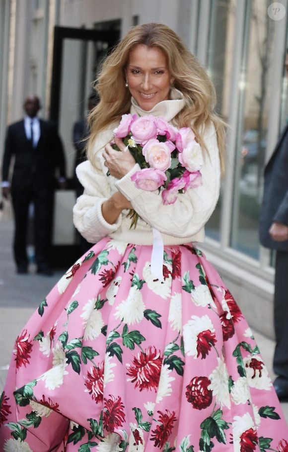 Celine Dion rayonnante et très souriante dans un ensemble pull écru et jupe bouffante fleurie salue ses fans à la sortie de son hôtel à New York, le 8 mars 2020 ©Backgrid USA / Bestimage