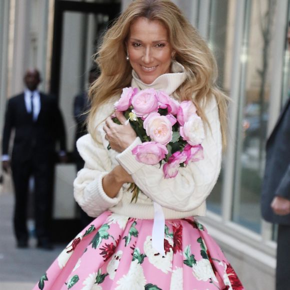 Celine Dion rayonnante et très souriante dans un ensemble pull écru et jupe bouffante fleurie salue ses fans à la sortie de son hôtel à New York, le 8 mars 2020 ©Backgrid USA / Bestimage