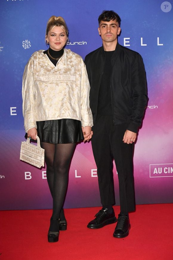 Il représente un timbre postal sur lequel on peut notamment distinguer un coucher de soleil en bord de mer, ainsi qu'un édifice qui ressemble à la basilique Notre-Dame de la Garde située à Marseille

Louane et son compagnon Florian Rossi  - Avant Première de " Belle " film animé japonais au Grand Rex à Paris le 6 décembre 2021 . © Veeren / Bestimage