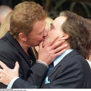 Johnny Hallyday embrasse Michel Sardou au mariage de ce dernier.