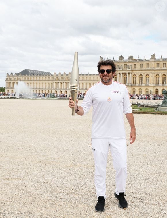 Le chanteur et acteur Patrick Bruel porteur de la flamme olympique des Jeux Olympiques de Paris 2024 (JO) au château de Versailles dans les Yvelines, France, le 23 juillet 2024. © Dominique Jacovides/Bestimage