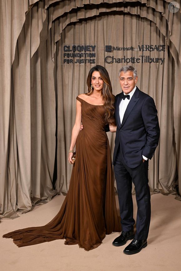 L’avocate portait une somptueuse robe drapée chocolat signée Versace, qui sublimait sa silhouette avec élégance.

Amal Clooney et son époux, George Clooney lors de la cérémonie des Albies au Musée d’Histoire naturelle de Londres. Photo par Backgrid UK/ Bestimage