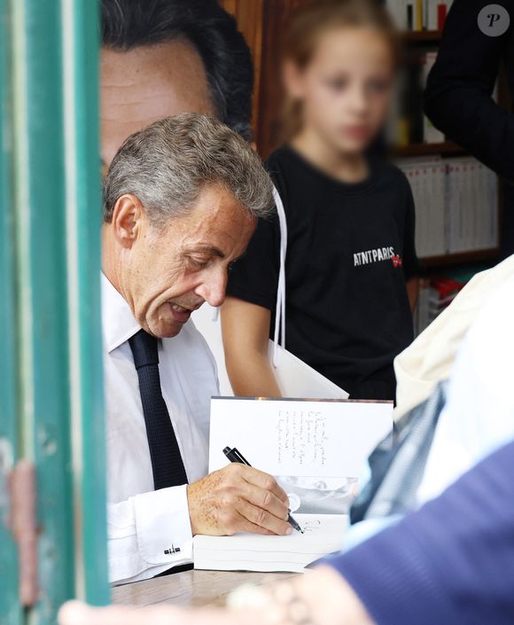 L'ancien président de la République française Nicolas Sarkozy dédicace son livre "Le temps des Combats" sous l'oeil attentif de sa fille Giulia à la Librairie du Marché à Deauville, France, le 1er septembre 2023. © Denis Guignebourg/Bestimage