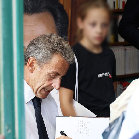 L'ancien président de la République française Nicolas Sarkozy dédicace son livre "Le temps des Combats" sous l'oeil attentif de sa fille Giulia à la Librairie du Marché à Deauville, France, le 1er septembre 2023. © Denis Guignebourg/Bestimage