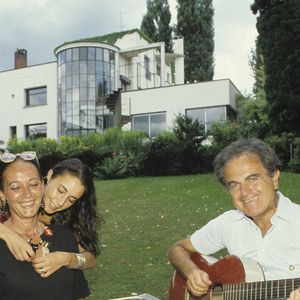 Archives - En France, à Garches, chez lui, de gauche à droite, son épouse Cécile Béart, sa fille Eve créatrice de bijoux et Guy Béart jouant de la guitare, tous autour d'une table dans le jardin. © Alain Canu via Bestimage
