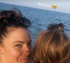 Sur cette image, on découvre Denitsa Ikonomova profitant de l'air marin. Le visage balayé par le vent, des lunettes de soleil à monture écaille remontées sur la tête, elle affiche un sourire naturel et apaisé tout en tenant son enfant serré dans ses bras face à l'étendue bleue.

Denitsa Ikonomova avec sa fille