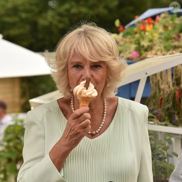 La femme du roi Charles III resplendit et affiche toujours un sourire radieux, à chaque évènement. 

Camilla Parker Bowles, duchesse de Cornouailles, mange une glace lors de sa visite au salon "Hampton Court Flower Show". Le 1er juillet 2015