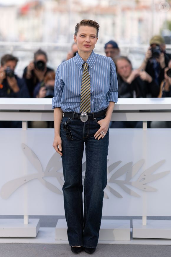 Pour casser le côté "costume cravate", elle a associé ce haut à un jean en denim brut taille haute, coupe droite, sublimé par une ceinture en cuir noir ornée d'une massive boucle ovale argentée. Et puis, à ses pieds, on devinait de discrets escarpins noirs à bouts pointus.

Mélanie Thierry au photocall du film "La Vie D'Une Femme" lors du 79ème Festival International du Film de Cannes, France, le 14 mai 2026. © Jacovides-Moreau/Bestimage
