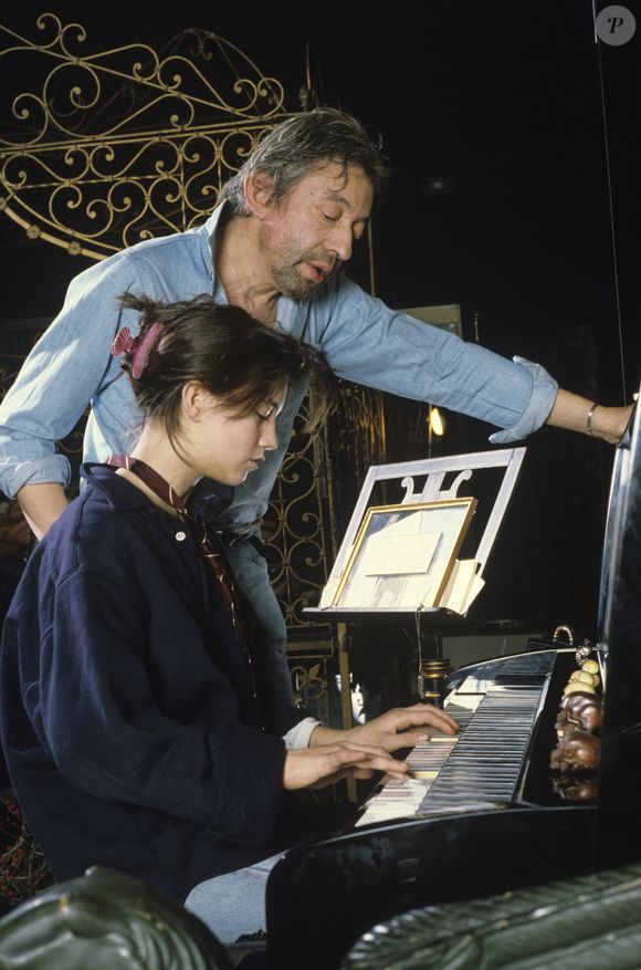 En France, à Paris, Serge Gainsbourg chez lui avec sa fille Charlotte dans son hôtel particulier de la rue de Verneuil, posant au milieu de son bric-à-brac où il entasse des objets hétéroclites en mai 1985.  © Michel Marizy via Bestimage