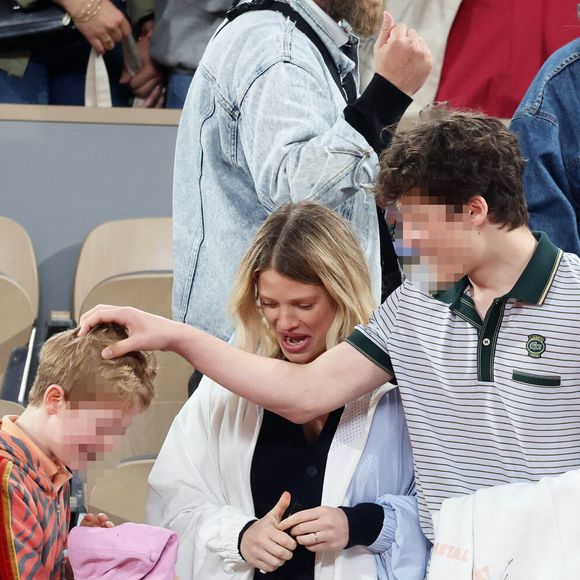 Roman et Aliocha Haroche voient Carlos Alcaraz dédicacer leurs casquettes sous le regard de leurs parents, Mélanie Thierry et son compagnon Raphaël - Les célébrités dans les tribunes des Internationaux de France de tennis de Roland Garros 2024 à Paris, le 29 mai 2024. 
© Jacovides / Moreau / Bestimage
