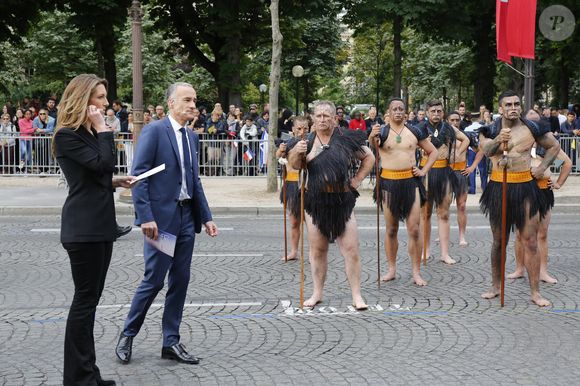 Les journalistes de la chaîne de télévision TF1 Gilles Bouleau et Anne-Claire Coudray avec les guerriers maoris de Nouvelle-Zélande lors de la célébration du Jour de la Bastille 2016, sur les Champs-Élysées à Paris, France, le 14 juillet 2016. Photo de Henri Szwarc/ABACAPRESS.COM