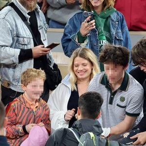 Roman et Aliocha Haroche voient Carlos Alcaraz dédicacer leurs casquettes sous le regard de leurs parents, Mélanie Thierry et son compagnon Raphaël - Les célébrités dans les tribunes des Internationaux de France de tennis de Roland Garros 2024 à Paris, le 29 mai 2024. 
© Jacovides / Moreau / Bestimage