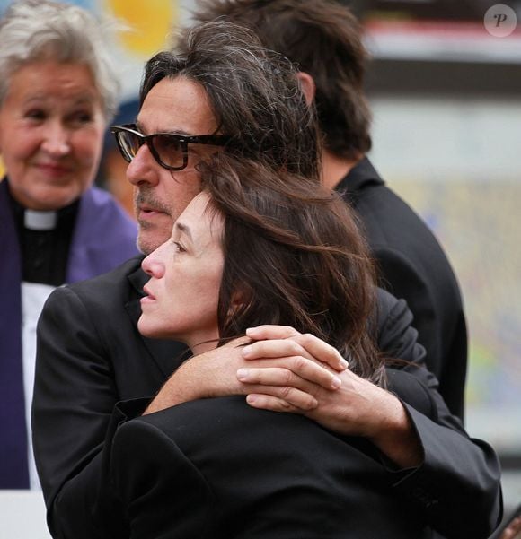 Alors elle tente de combler ce vide comme elle le peut. Charlotte Gainsbourg révèle ainsi vivre avec un objet ayant appartenu à sa mère. 
Yvan Attal et Charlotte Gainsbourg - Sorties des obsèques de Jane Birkin en l'église Saint-Roch à Paris. Le 24 juillet 2023
© Jonathan Rebboah / Panoramic / Bestimage