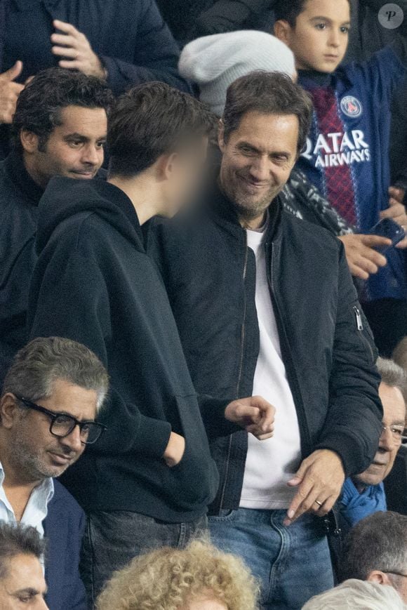 Grand Corps Malade et son fils - Célébrités dans les tribunes du match de Ligue des Champions entre le PSG contre le Bayern de Munich (1-2) au Parc des Princes à Paris le 4 novembre 2025. © Cyril Moreau/Bestimage