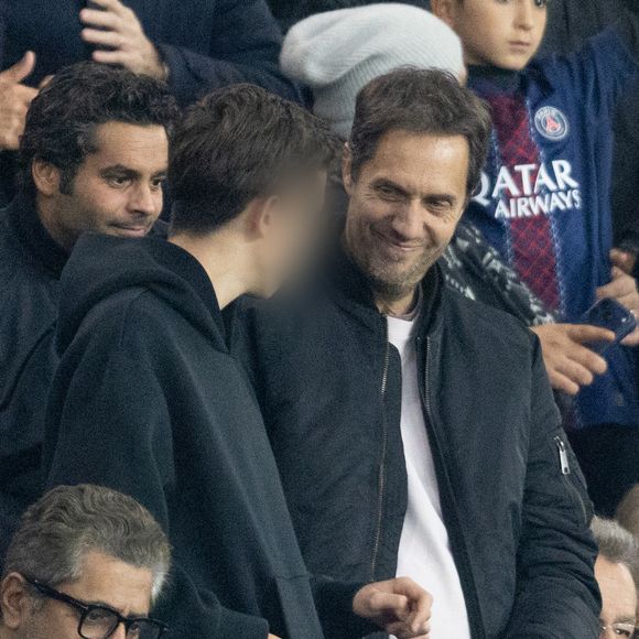 Grand Corps Malade et son fils - Célébrités dans les tribunes du match de Ligue des Champions entre le PSG contre le Bayern de Munich (1-2) au Parc des Princes à Paris le 4 novembre 2025. © Cyril Moreau/Bestimage