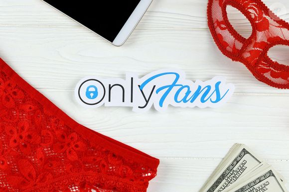 Logo Onlyfans en papier avec des billets de banque, un masque rouge et de la lingerie rouge sur une table en bois blanc. OnlyFans is content subs Photo by Alamy/ABACAPRESS.COM