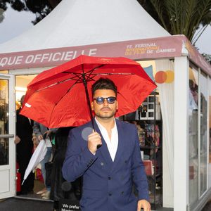 Kev Adams brave la pluie avec un parapluie rouge lors de la première journée du 77ème Festival de Cannes au Palais des Festivals à Cannes, France, le 14 mai 2024 dans le cadre du Photo by Cyril CHATEAU/ABACAPRESS.COM