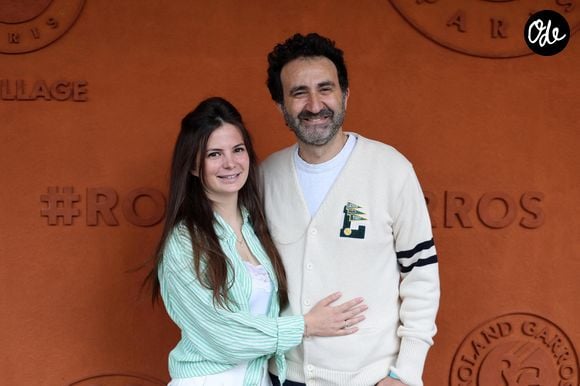 Sa femme Olivia partage elle aussi cette nouvelle aventure, mais loin du monde du spectacle. Elle exerce comme nez en parfumerie, un métier bien différent.

Mathieu Madénian et sa compagne Olivia Madénian au village lors des Internationaux de France de Tennis de Roland Garros 2025. Paris, le 28 mai 2025. © Jacovides / Moreau / Bestimage