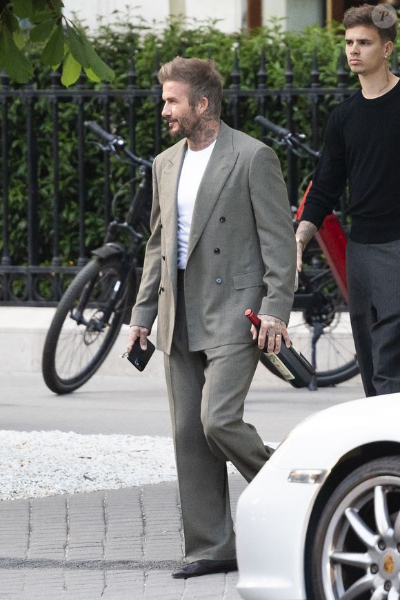 Exclusif - La famille Beckham (David Beckham, sa femme Victoria, Cruz Beckham, sa compagne Jackie Apostel, Roméo Beckham, sa compagne Kim Turnbull et Harper Seven) arrive à son hôtel fétiche "La Réserve" pour fêter les 50 ans de David Beckham (2 mai 1975) à Paris, France, le 2 mai 2025. David sort avec une bouteille de rouge pétrus Pomerol (surement l'année de sa naissance) à la main . © Bestimage