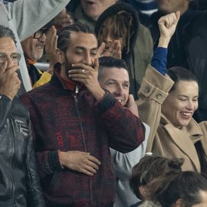 Roschdy Zem et son fils Chad Zem, Michou, , Adriana Lima et son compagnon Andre Lemmers, Benjamin Millepied et son fils Aleph - Célébrités des les tribunes lors du match aller du quart de finale de Ligue des champions entre le PSG et Aston Villa (3-1) au Parc des Princes à Paris le 9 avril 2025. © Cyril Moreau/Bestimage