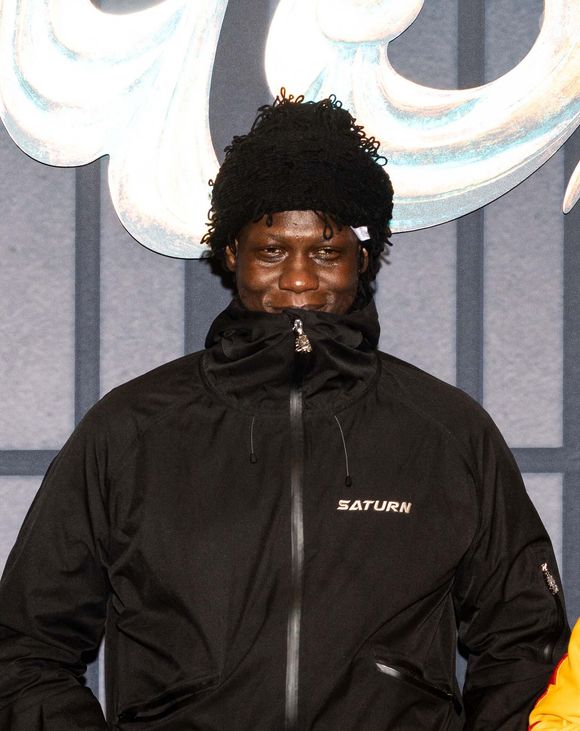Il s'agit du rappeur Doums.

Doums lors de la première du film "Yoroï" au cinéma le Grand Rex à Paris le 16 octobre 2025.

© Julien Sarkissian / Bestimage