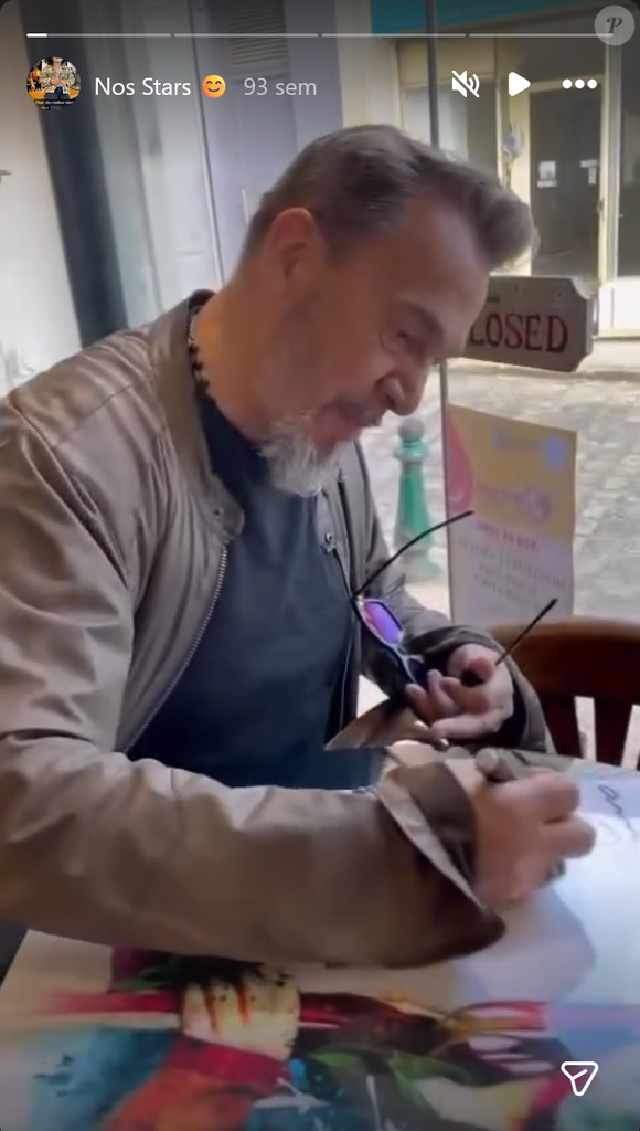 Florent Pagny attablé à La Table du Coq, en train de signer un tirage à son effigie.