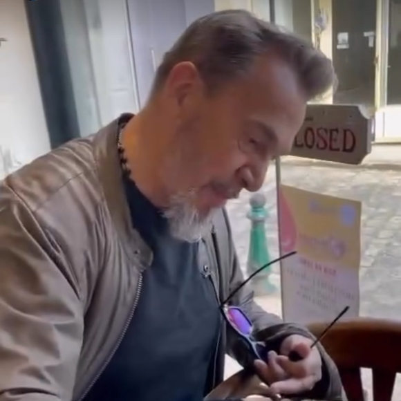 Florent Pagny attablé à La Table du Coq, en train de signer un tirage à son effigie.