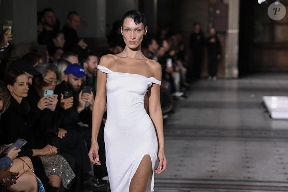 Bella Hadid arrive sur le podium vêtue d'une simple culotte, c'est alors que trois hommes pulvérisent une solution sur le mannequin américain et en quelques minutes, une robe minimaliste à manches à épaules dénudées et fente latérale à été créée en clôture du défilé Coperni Collection Femme Prêt-à-porter Printemps/Eté 2023 lors de la Fashion Week de Paris (PWF), France, le 30 septembre 2022.