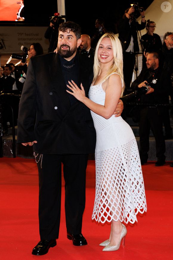 Kim Higelin s'est illustrée dans une création immaculée à la coupe audacieuse, à savoir une robe blanche dont le buste ajusté à fines bretelles mettait en valeur sa silhouette, avant de se transformer en une jupe ajourée. 

Artus et sa compagne Kim Higelin - Montée des marches du film "Jim Queen" lors du 79ème Festival International du Film de Cannes le 18 mai 2026.

© Moreau / Jacovides / Bestimage