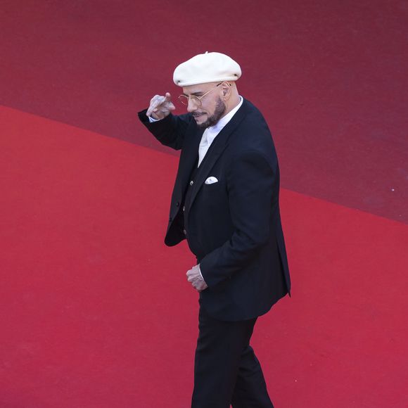Loin d'être un simple hommage cliché à la culture française, ce choix fashion a une signification touchante. 

John Travolta - Montée des marches du film " Karma " lors du 79ème Festival International du Film de Cannes, le 15 mai 2026. © Camilla Canalini / Bestimage